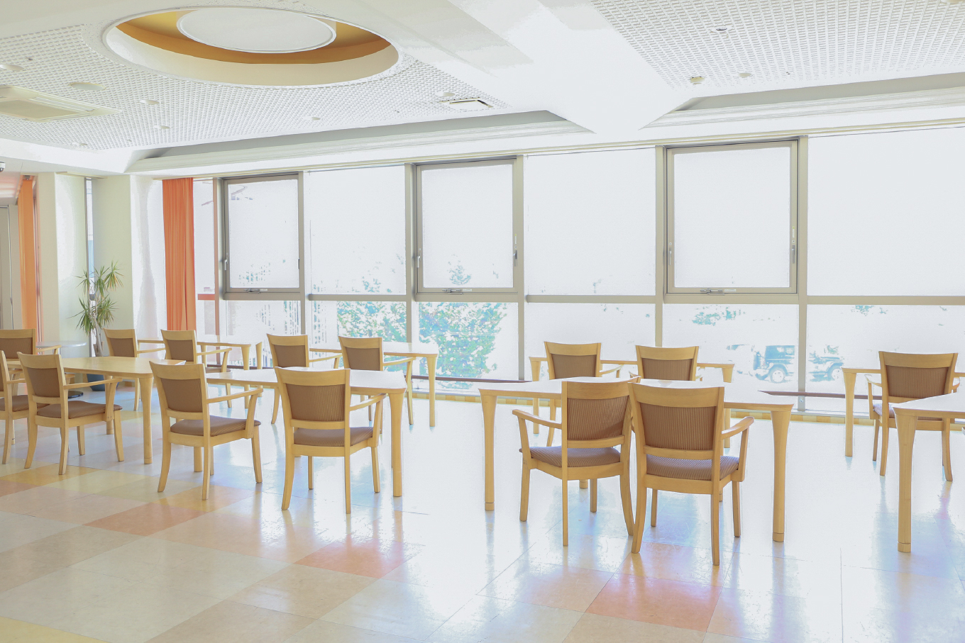 木製の椅子と机が並び太陽の差す部屋の写真